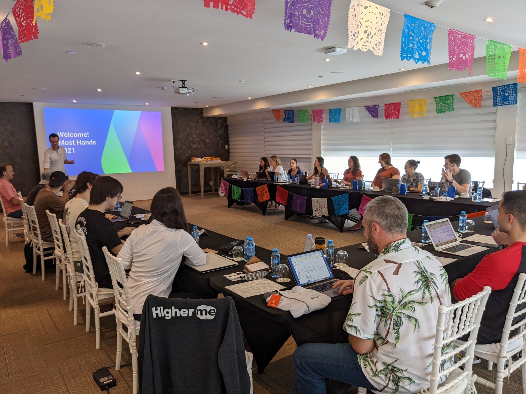 Team of coworkers sitting around a large U-shaped table_HigherMe_Flok