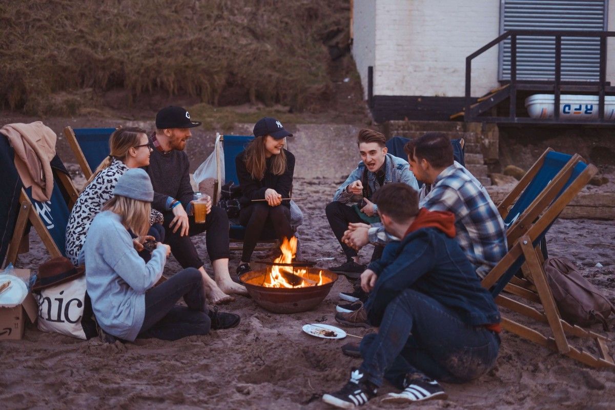 people sitting around a fire at the beach_how to plan work activities_company retreat_flok